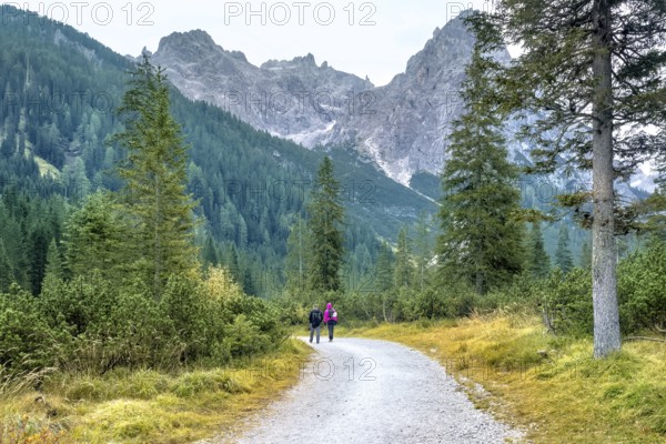 Hiking trip, Dolomites landscape. Pair of tourists is walking along a wide trail in the Dolomites. The Tofane Group in the Dolomites, Italy