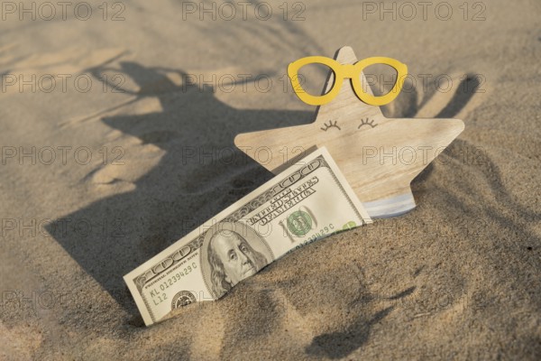 Money american hundred dollar bills in sandy beach with starfish. Concept finance saving money for holiday vacation. Costs in travel holidays. Shadows