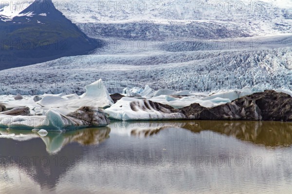 Blocks of ice are reflected in smooth water. Jokulsarlon glacial lagoon. The imposing scenic lagoon in the north of Iceland. Glaciers and icebergs among cold mountains