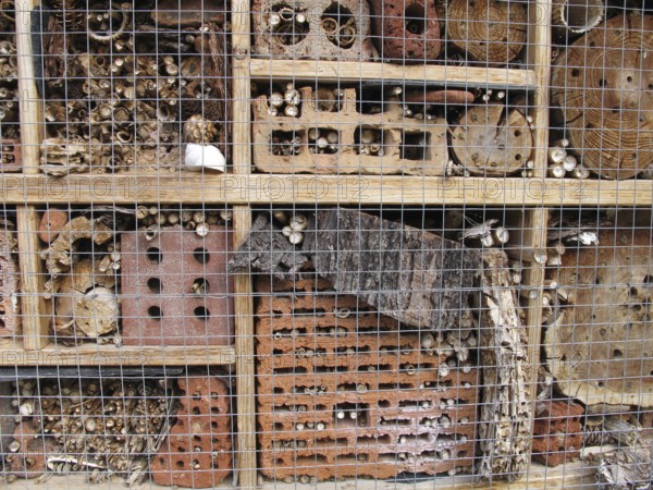 Insect hotel with bricks, bamboo sticks, bark and logs