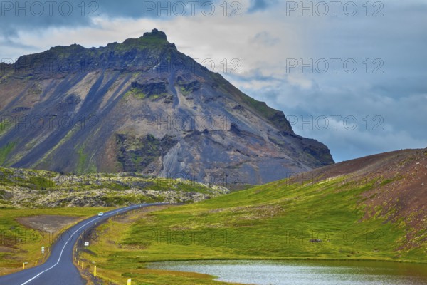 The road passes through the picturesque landscape in the mountains and lakes. Cloud Iceland in the summer