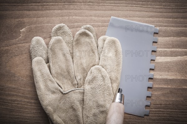 Working glove and putty knife on wood board