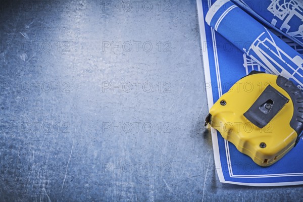 Assortment of blue construction plans measuring tape on metallic background