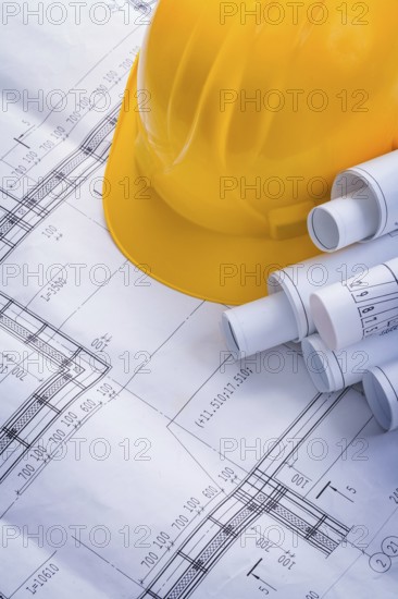 Rolls of blueprints and yellow helmet