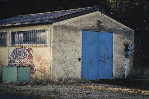 Wildberg, Calw, Baden-Württemberg, Germany, Rural hut with blue door and graffiti in front of forest