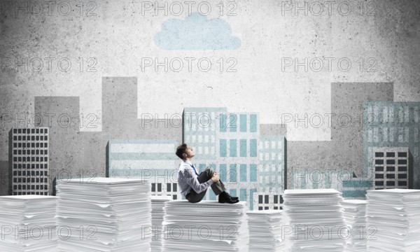 Thoughtful businessman looking away while sitting on pile of documents with drawn cityscape on background. Mixed media
