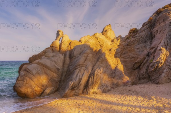 Vourvourou, Chalkidiki or Halkidiki, Greece summer sunset scenery with turquoise sea, forest green mountains and rocks at Fava sandy beach