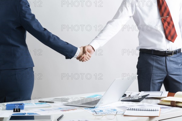 Businessman and businesswoman handshaking after good deal. Business consultation and cooperation in office. Corporate teamwork and partnership. Businesspersons greeting or finishing successful meeting