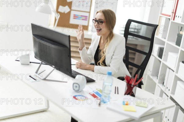 A beautiful young blonde girl in a white jacket and black blouse is working in the office. photo with depth of field
