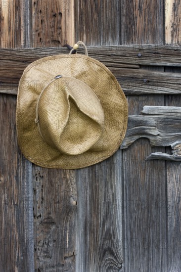 Straw cowboy hat and weathered wood of old barn in Colorado