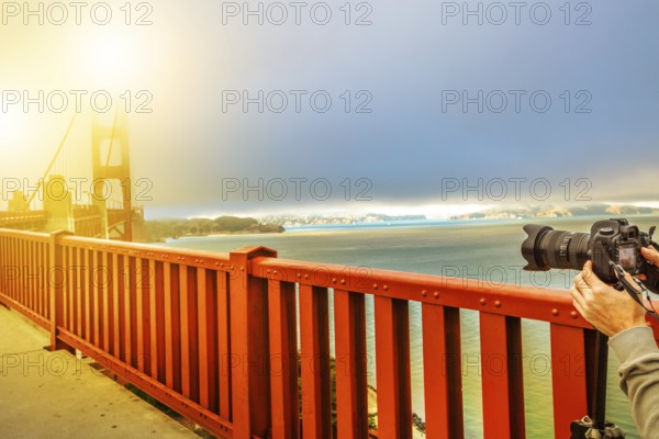Camera taking a shot of Golden Gate Bridge and red railing, San Francisco, California, United States. Pedestrians perspective of bridge.Concept of hobbies, travel, tourism and professional photography