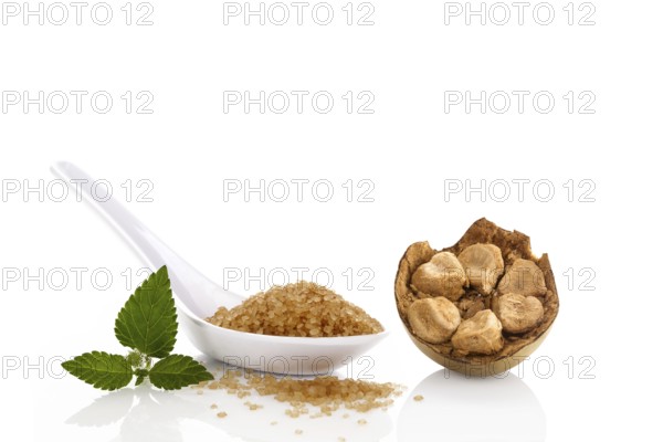 Heap of brown cane crystallized sugar in white spoon and monk fruit, luo han guo isolated on white background