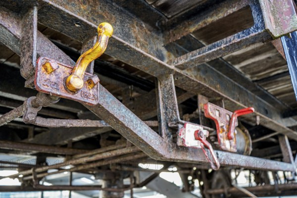 Close-up of rusty wagons with distinctive red levers on a structure, 27568 Bremerhaven
