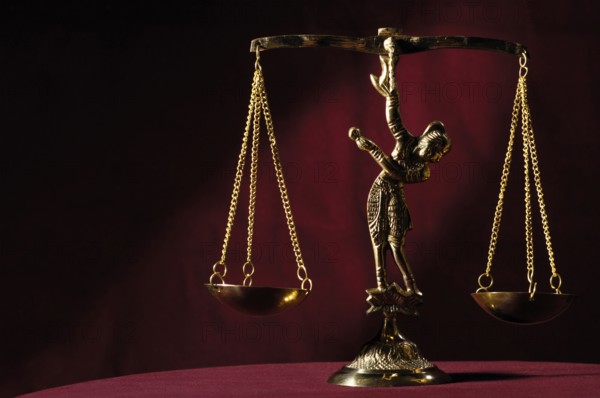 Stock photo of Shiny golden empty balanced vintage justice scales isolated on dark red background Atristic still life conceptual symbol for justice law and attorney