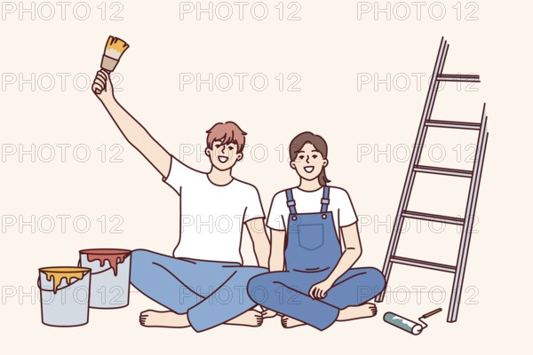 Couple makes repairs in apartment with own hands and sits on floor near ladder and buckets of paint for painting walls. Cheerful man and woman rejoice at opportunity to make diy repairs in room