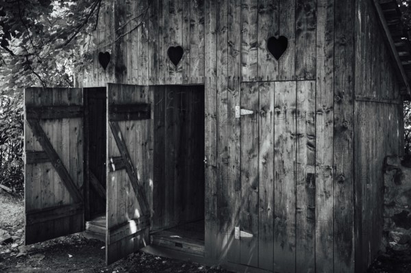 Open doors to old wooden outhouses. Romania