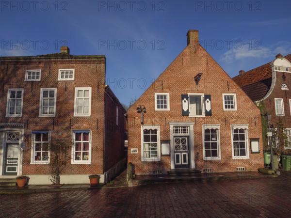 Two brick houses with beautiful façade and balcony under a blue sky, Greetsiel, East Frisia, Germany