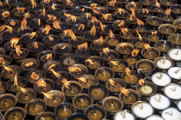 Group of oil religious candles glowing with orange flames on a hindu temple. Symbols of faith and religion and for wishes and prayers