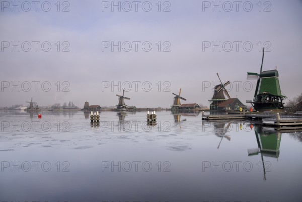 Windmills along the river Zaan in the Dutch traditional village Zaanse Schans which is one of the busiest tourist locations in the Netherlands