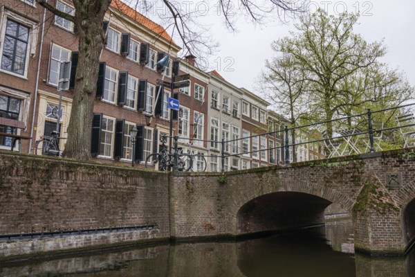 A canal with a stone bridge and historic buildings in the background, bicycles next to the bridge, The Hague, Netherlands