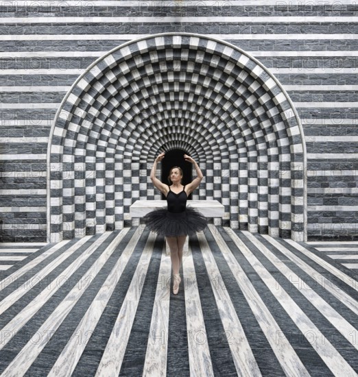 Ballerina in a black tutu poses in front of modern, stripe-patterned, symmetrical granite architecture, San Giovanni Battista, Mogno, Ticino, Switzerland