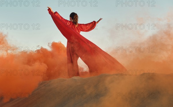Woman in red dress dancing in the desert at blue sky