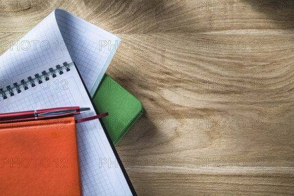 Spiral checked copybook notepads biro pen on wooden board