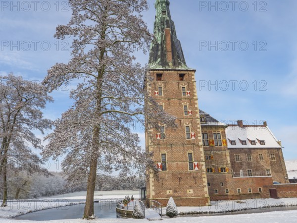 A castle with high towers, snow-covered trees and a clear sky in winter, raesfeld, münsterland, germany