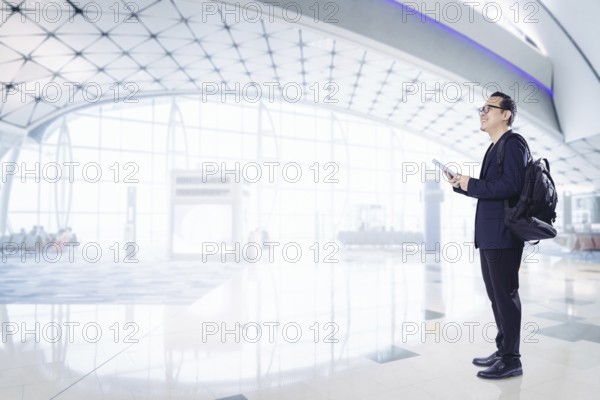Junger Geschäftsmann mit digitalem Pad lächelnd glücklich im Flughafen warten Halle