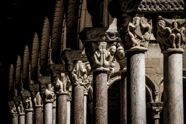 Medieval stone columns with intricate carvings and arches create a shadowy and ornate architectural scene, Ripoll Monastery, romansque, Catalonia, Spain
