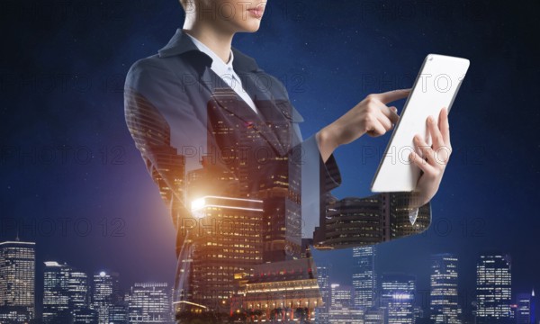 Businesswoman using tablet computer. Double exposure concept with night city and woman in business suit. Real estate investment and development. Digital technology in strategy planning and management