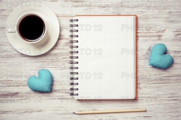 Coffee cup notepad pencil and two hearts on wooden surface