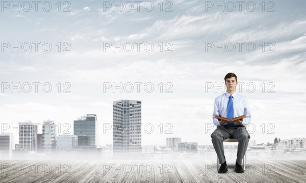 Young businessman with book on office chair