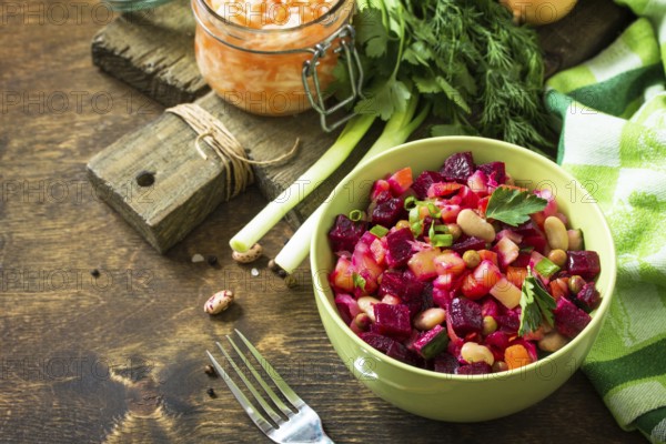 Beetroot salad vinaigrette with sauerkraut, pickled cucumber and vegetables on a wooden rustic table. Copy space