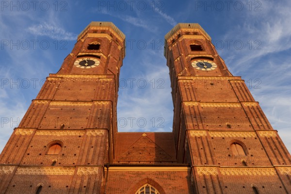 The two towers of the Church of Our Lady in the historic centre of Munich in front of a clear cloud cover with heron clouds and a blue sky in an extreme lower view