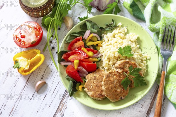 Healthy vegan food, keto or paleo diets. Homemade red fish cutlets with bulgur and fresh vegetable salad on a wooden table. Top view flat lay background