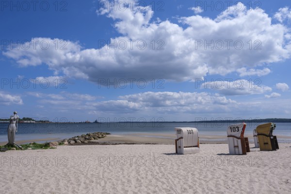 A quiet beach with beach chairs and a sculpture at the water's edge, Eckernförde, Schleswig-Holstein, Germany