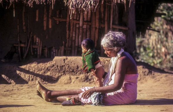 A jenu kurumba tribal old woman with her grandson. Baby urinating in Nagarahole tribal settlement Karnataka, South India, India, Asia