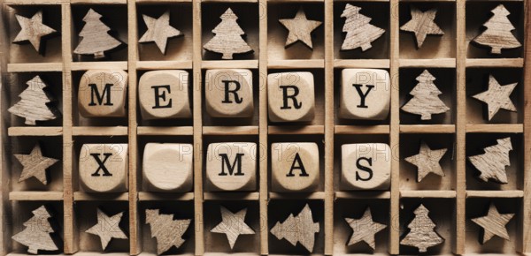 Small wooden dices in a box with the words Merry x-mas, star and tree shape decoration around