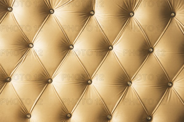 Beige soft textile background with symmetrical buttons on the corners of diamonds. Soft and expensive furniture elements. Luxury background