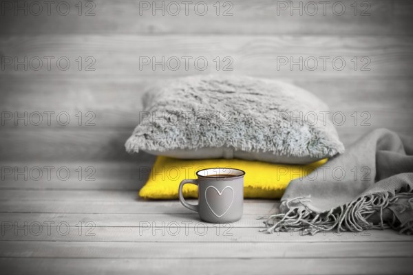 Pillows and cup of beverage against blurred wooden wall as symbol of warmth and comfort at home