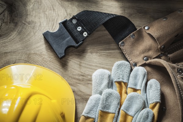 Leather belt Safety gloves Safety helmet on wooden board