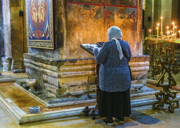MTSKHETA, GEORGIA - OCT 25, 2018: Woman praying in Svetitskhoveli Cathedral in the historic town of Mtskheta, Georgia