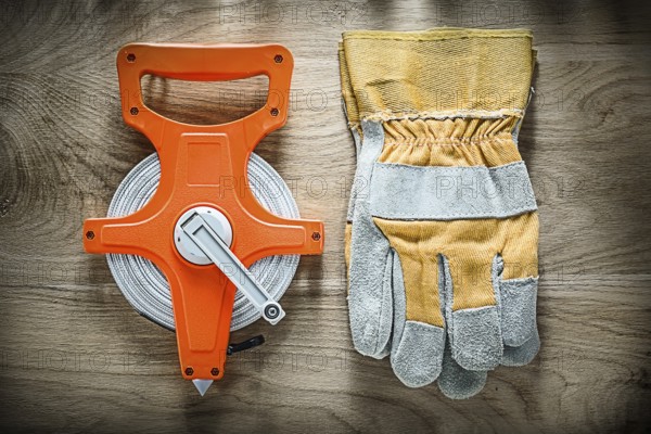 Pair of safety gloves Tape measure on wooden board