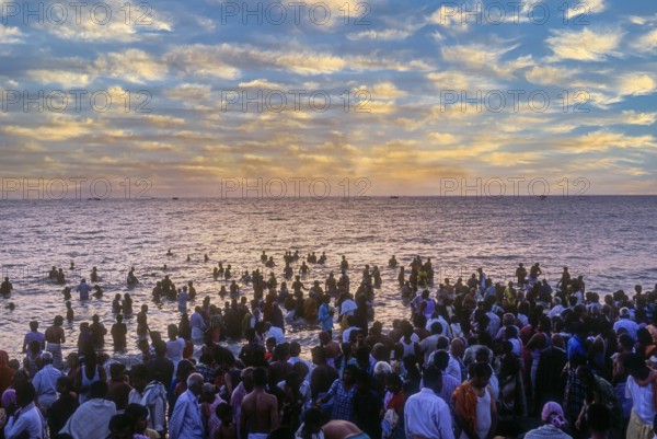 Devotees taking a dip in the holy waters of the Agni Theertham in Rameswaram, Tamil Nadu, South India, India, Asia. Bay of Bengal. Sunrise