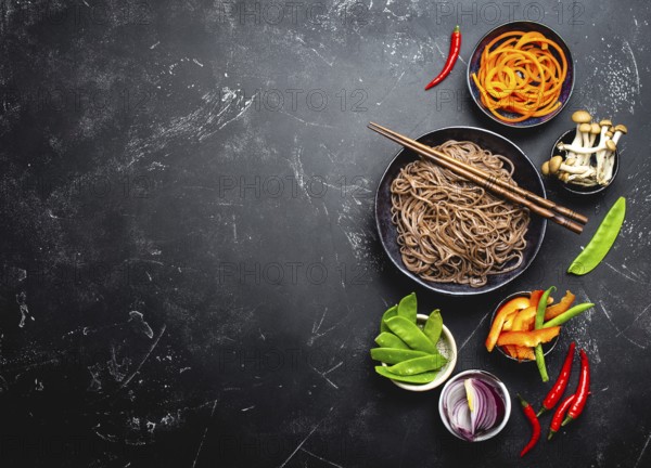 Ingredients for making stir-fried noodles soba. Cut fresh vegetables, mushrooms, boiled soba noodles in bowl with chopsticks ready for cooking, black stone background, space for text, top view