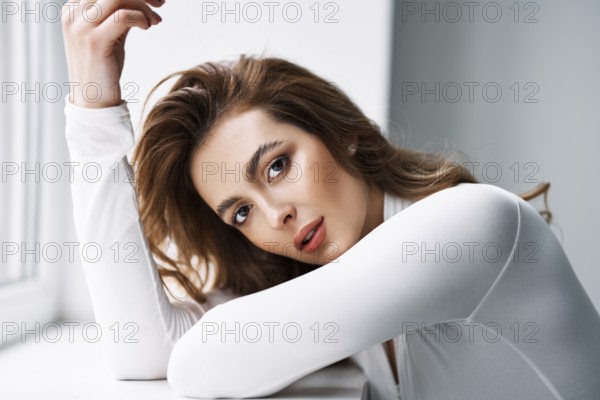 Close up portrait of sensual pretty young woman. Beautiful female model in white cloth with clean skin and sable style eyebrows posing in studio