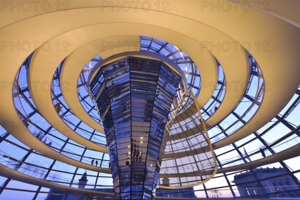 Reichstag in Berlin, the photo shows the dome of the Reichstag with the walkable spiral inside. The architect Norman Foster designed the dome. The glass dome provides the plenum with natural daylight and serves as ventilation. Reichstag building in Berlin. The large glass dome at the very top of the Reichstag has a 360-degree view of the surrounding Berlin cityscape. The main hall of the parliament below can also be seen from inside the dome, and natural light from above radiates down