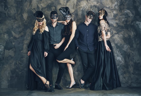 Group of people in masquerade carnival mask posing in studio. Beautiful women and men wearing venetian mask. Fashion, party, friends concept