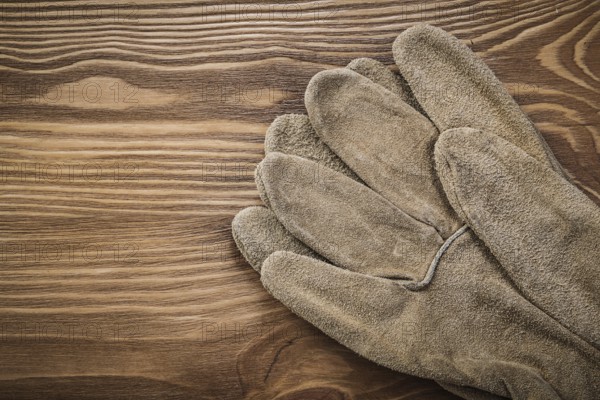 Brown protective gloves on vintage wooden board Construction concept